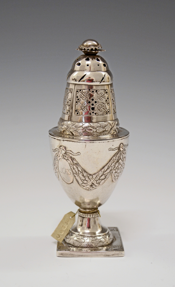 Fra protokollen: Sukkerdrysse av sølv, urne form, Ludvig 16. stil. Stemplet synes at være Kristiansands bystempel.

Oppført som sukkerdrysse i protokollen, men kan det være en "sanddrysse" - for fjerning av overflødig blekk ved bruk av fjærpenn og blekk?