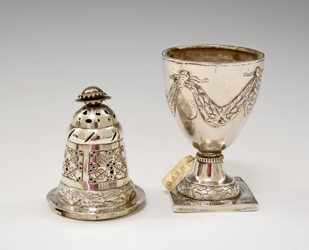 Fra protokollen: Sukkerdrysse av sølv, urne form, Ludvig 16. stil. Stemplet synes at være Kristiansands bystempel.

Oppført som sukkerdrysse i protokollen, men kan det være en "sanddrysse" - for fjerning av overflødig blekk ved bruk av fjærpenn og blekk?