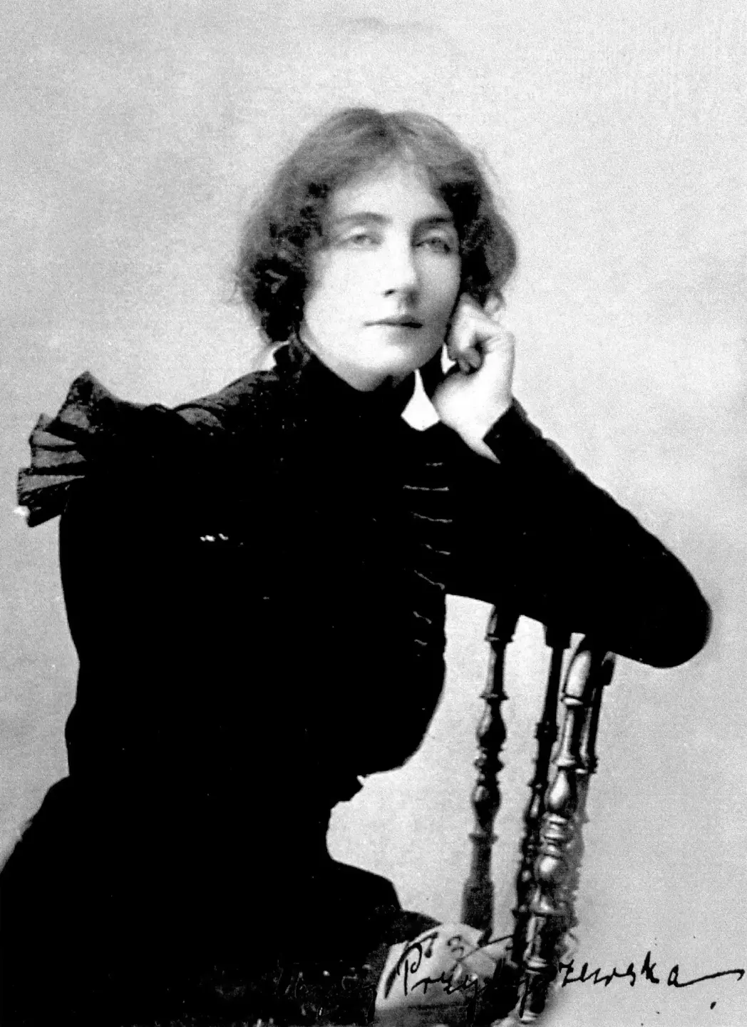 Dagny Juel, fotografert i Warzawa våren 1901. Dagny sitter på en stol og lener albuen mot stolryggen.