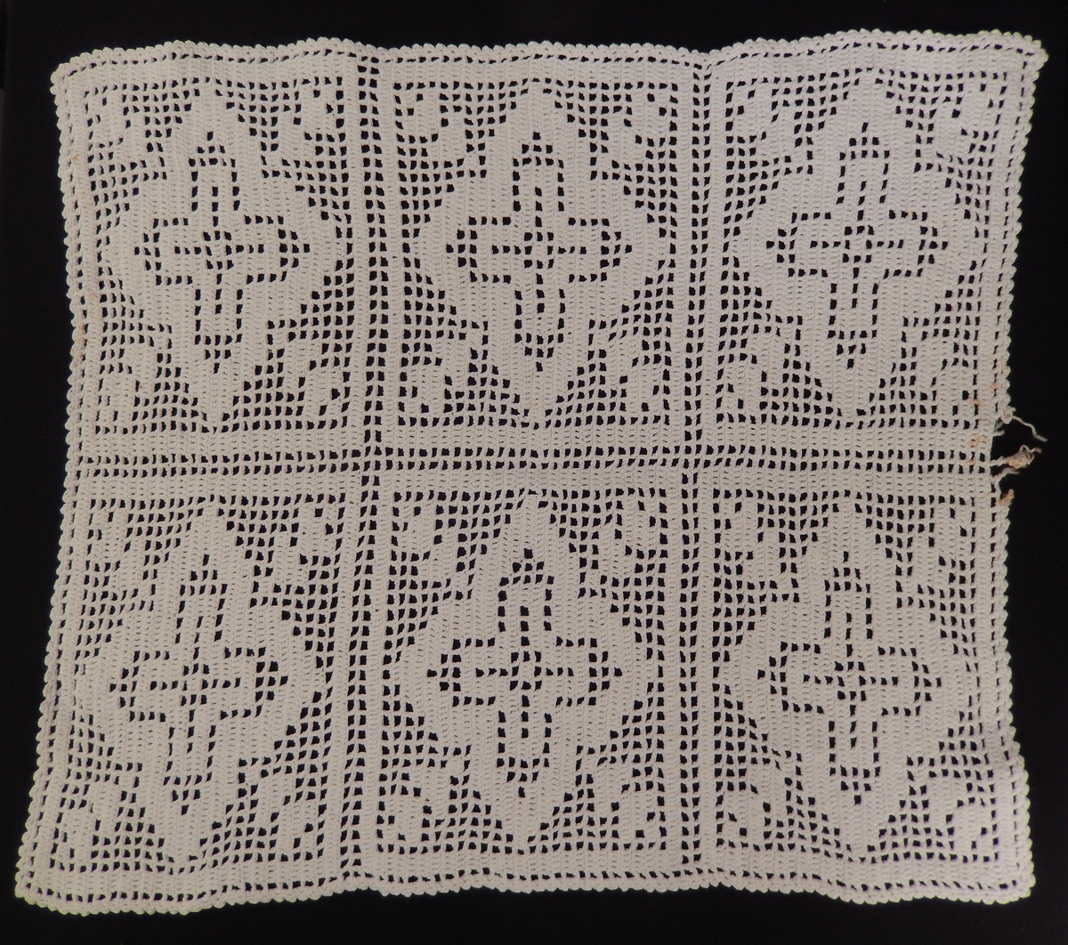 En dokkeseng i kurvfletting fra ca. 1905, med løse sengegavler, en madrass, et laken (glasshånklr med monogram), en overmadrass, to puter, med putevar, en dyne og et heklet sengeteppe.