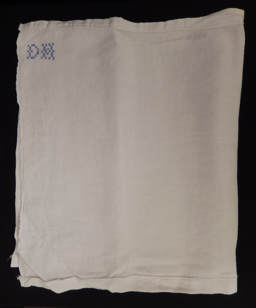 En dokkeseng i kurvfletting fra ca. 1905, med løse sengegavler, en madrass, et laken (glasshånklr med monogram), en overmadrass, to puter, med putevar, en dyne og et heklet sengeteppe.