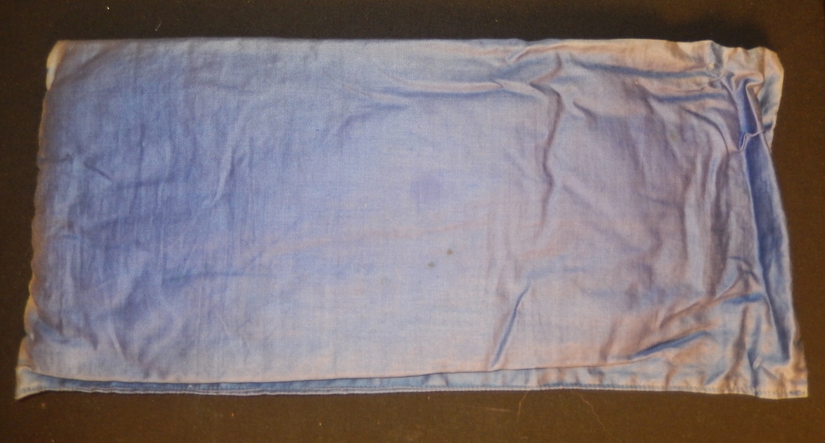 En dokkeseng i kurvfletting fra ca. 1905, med løse sengegavler, en madrass, et laken (glasshånklr med monogram), en overmadrass, to puter, med putevar, en dyne og et heklet sengeteppe.