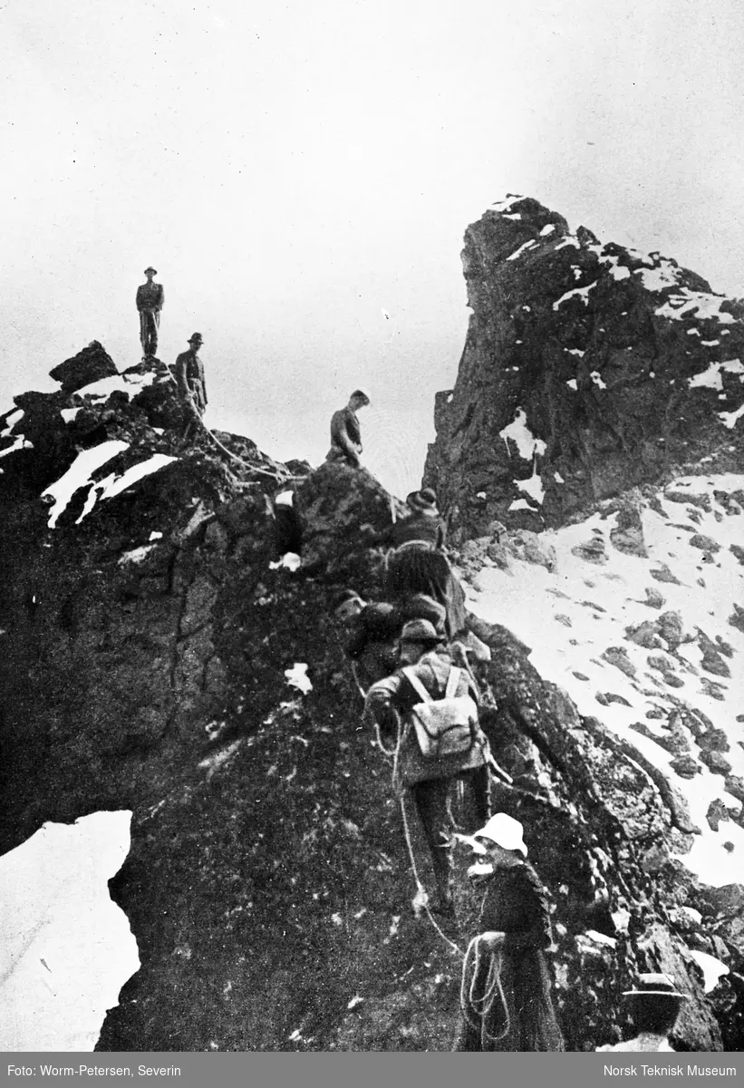 En gruppe personer gaår i tau etter hverandre opp en fjellrygg