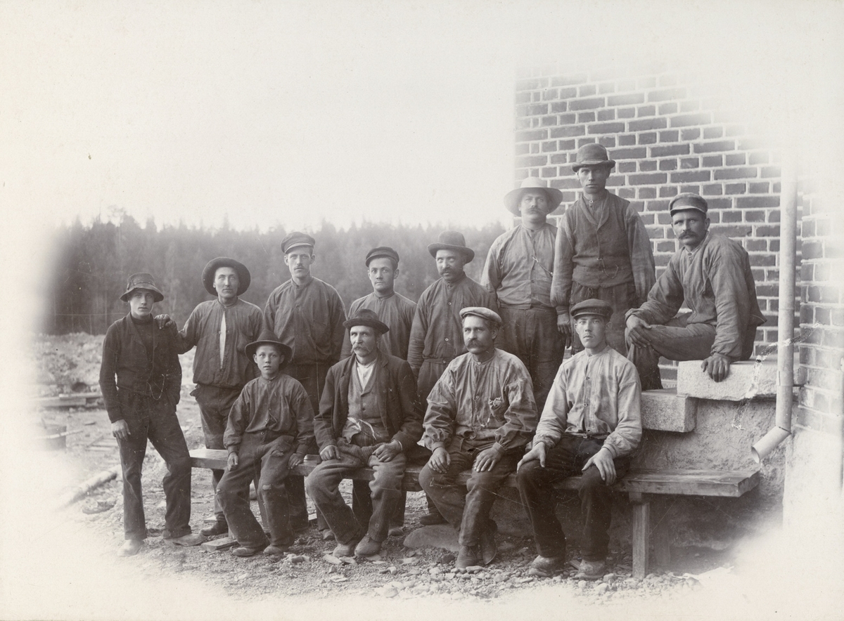 Arbeidsfolk i busserullar framfor teglsteinsbygning. 