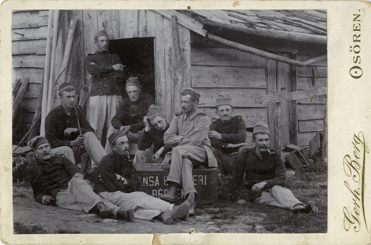 Ni menn tek røykepause i militæret - oppstilt rundt ein kasse frå Hansa Bryggeri, Bergen. Emil Clausen (2. frå høgre).