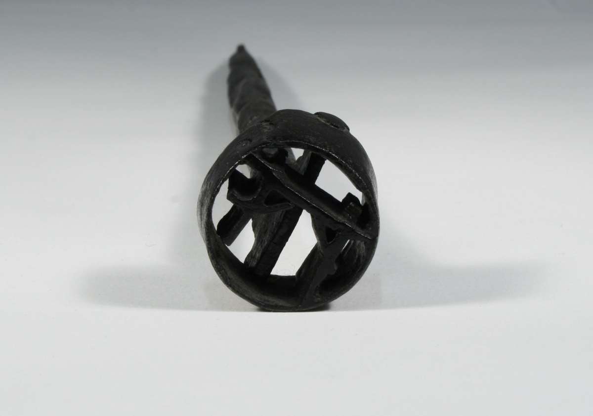 Består, foruten selve brennemerket, av en tange for montering av håndtak. Brennemerket har form som et galgesymbol med en sirkel rundt. Har trolig opprinnelig vært påmontert et trehåndtak som nå er borte.