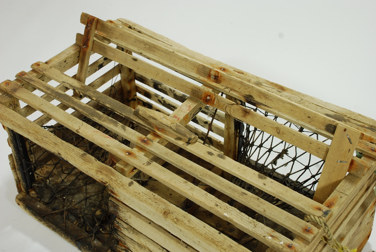 Typisk eksempel på kasse-tene, hvor original fiskekasse er benyttet som fangstfelle. Kort og kompakt kasse med bunn av gammel utrangert fiskekasse. Horisontale lekter overfor selve kassebordene. Grovt hjemmelaget garn av nylontau med tverrknuter - et sjeldent fenomen! 
En inngang på hver langside. Ingen fangstkammer. 
Agnpinne av grov metalltråd. 

Kalven: Et tynnere tau er festet til garnet i kalven tversgående, før å gjøre maskene mindre. Kalvene er impregnert med tjære, trolig for å gjøre tauet mørkt slik at hummeren går inn. Kalvene er festet til åpningen med en lekte. Garnet festet rundt en lekte som deretter er spikret fast i tena. Metallringer i kalveåpningene. 

Lokk av to lekter. Lukkeåpning; moderne skyvepatent med vrider. Skyvemekanisme; skyves bort og vippes opp. 
En liten metallplate er festet vertikalt over to lekter, - uvisst hvorfor. Støpt betonghelle i hver ende, dekker hele bredden. E.V. risset inn i den ene. 

Komplett tauverk med væler. Tau i naturfiber. Festet til tena med syntetisk tau. Ekstra tau flettet inn i nederste del for å gi tauet flytekapasitet. 
Væle: malt hvit med en rød stripe ca. 10 cm fra bunnen. Bunnplata malt rød. E.V. skåret inn i treverket på det hvite feltet. Spiss ende med hull til tau. 
Tolver og sekser væler: 1) 4 korkbiter. Festet til tauet med blått syntetisk tau. Malt helt hvit, men rød i bunnen. 2) 6 korkbiter. Hvitmalte, rød i enden. Festet til tau med tau i naturfiber.