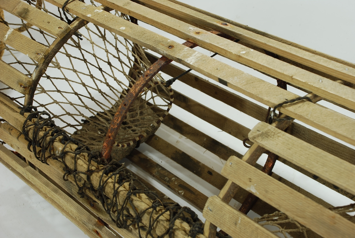 Rund/ sylindrisk sprøtt-tene. Hjemmespunnet garn med store masker. To motstående innganger i kortsidene. Intet fangstkammer. Kalveringer i metall, ovale i formen tilpasset krabbens fasong. Ovalformet åpning i toppen forsterket med ubehandlede barkkledde enerkvister som er formet til. Metallgjorder virker solide og kan være spesiallaget. Agnspyd i metall horisontalt plassert med ekstra sperre i kalveringen. Synkestener i granitt i hver ende, bundet fast med sort tauverk. Åpning med gammeldags lukkepatent med garn og håndspikket pinne. Tena bærer preg av tidligere å ha vært tjæret/ barket. 

Store mengder gresstau og fem væler, tre stk. i treverk og to stk. av kork. 
Hvitmalte trevæler i tre størrelser:
Størst: 63x9 cm.
Mellomst: 51x9 cm. 
Minst: 41x9 cm.
Alle har profilerte kanter og er hvitmalte med sort ende (tjæret). Malingen er nesten slitt av. K.V er skåret inn i de tre fløtene.
Korkvæler:
Lengde: 22cm
Omkrets 32 cm.
K.V risset inn i den ene.