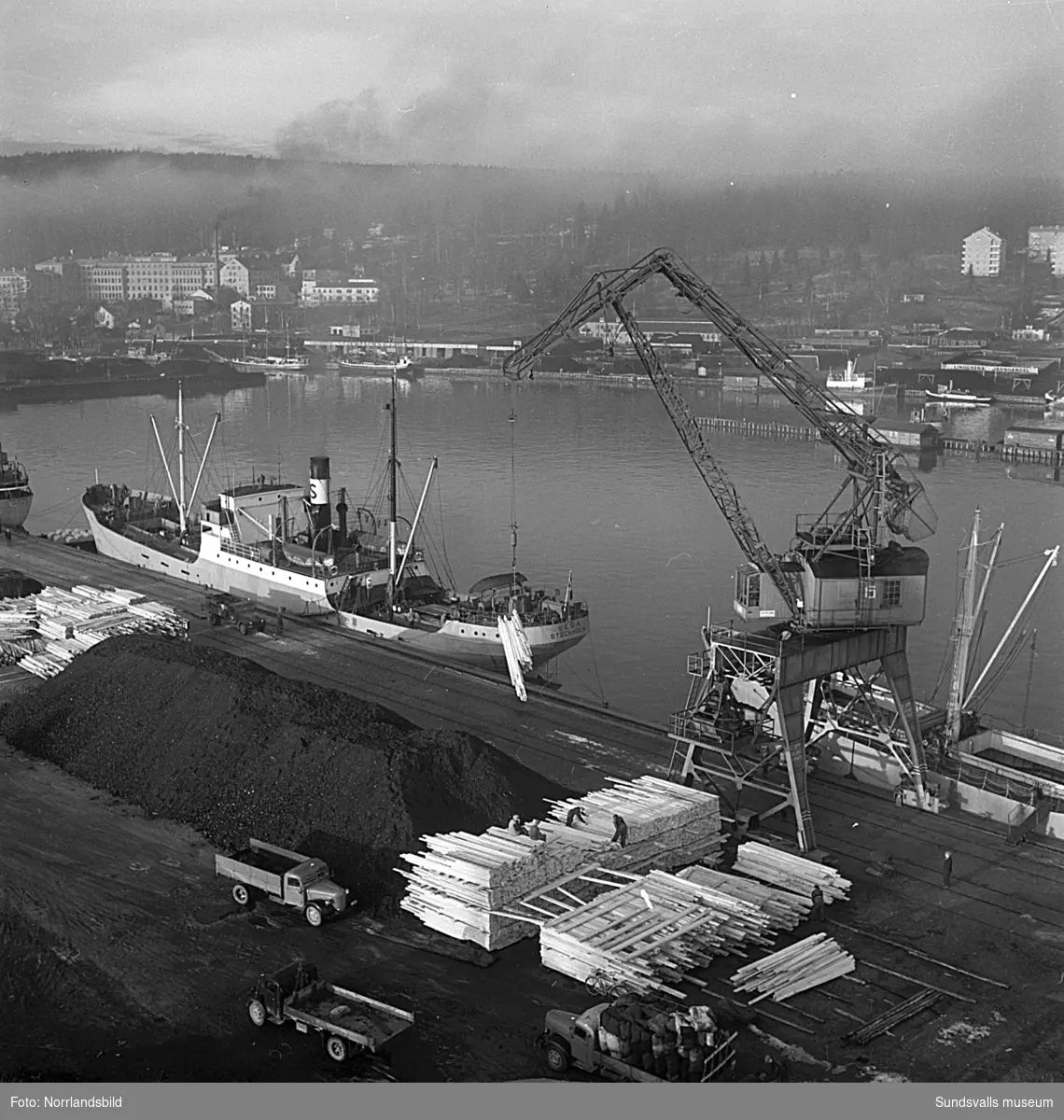 En serie bilder från verksamheten i hamnen i början av 1950-talet. Båtar, pråmar, kranar, kolhögar och magasin.