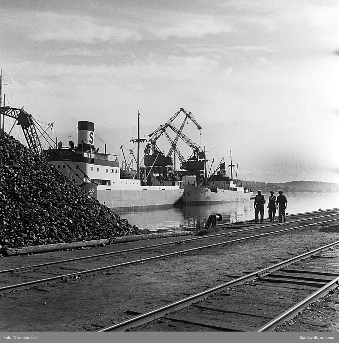 En serie bilder från verksamheten i hamnen i början av 1950-talet. Båtar, pråmar, kranar, kolhögar och magasin.