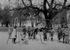 Lekande barn i parken, lekplatsen, två gungor.
Kindergarten, Oskarsparken.
Fröken Maria Kjellmark