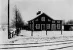 Bostadshus med trädgård. Järnvägsspår vid sidan av staketet.