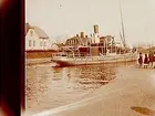 Skebäck nedanför slussen.
Bogseringsbåten Hjälmaren.
Stereofotografi.
Huset till vänster på bilden kallas Villa Östanå och byggdes 1902 av fabrikören Leo August Pollnow som var född i Pommern 1855. Han startade också Pollnows Färgeri (Örebro Nya Ångfärgeri och Kemiska Tvättanstalt).