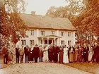 Tvvånings bostadshus med veranda i snickarglädje, 28 personer framför huset.
Direktör Edstams 60 årsdag.