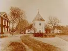 Tvåvånings bostadshus med frontespis till vänster på bilden, Olshammars kyrkan rakt fram.
(Två bilder på samma glasplåt)