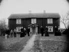 Tvåvånings bostadshus, grupp 10 personer framför huset.
Carl G. Carlsson