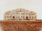 Almby skola, tvåvånings skolbyggnad.
Skolbarn framför skolan.