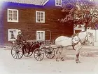 Tvåvånings bostadshus i trä, vattenpump på bakgården.
Häst spänd för landå med en man i. Mannen är hästhandlare och åkeriägare Gotthold Sandblom. Han var en av landets största hästhandlare vid den tiden.