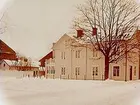 Vinkelbyggt tvåvånings trähus med balkong och glasad veranda, baksidan.
Robert Eriksson