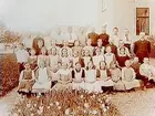 Almby skola, 38 skolbarn med lärare.
Skolbyggnad i bakgrunden.
Magister Lundells klass, Almby.