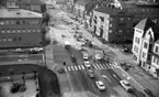 Trafik i korsningen Rudbecksgatan/Trädgårdsgatan.
Rubrik till bilden: Vänstertrafik- höger 4 september 1967.
Högeromläggningen genomfördes den 3 sept 1967, kl 05:00. På bilden är högertrafik förberett men fortfarande vänstertrafik, så bilden är tagen strax innan omläggningen.