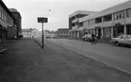 Frövi, Handikappade 17 november 1966

En gatubild från centrala Frövi. En pojke kommer åkande på moped på gatan. Bilar och en affär, en bokhandel samt en frisörs klippstuga syns i bakgrunden.