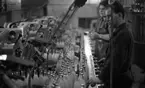 Kopparbergs bryggeri 1 18 februari 1967

Två industriarbetare klädda i arbetskläder står vid det löpande bandet inne i  Kopparbergs bryggeri. På bandet kommer läskedrycksflaskor åkande.