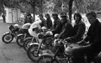 Knuttar och spättor 22 juni 1965.

Tio stycken ungdomar med motorcyklar i förgrunden. Nyfiken kvinna kikar fram bakom glasskiosken.