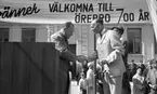 Knytkalaset 5 juli 1965.

Harald Aronsson tilldelas ett standar av en herre med texten 700 år på samt det krönta Ö-et. Jubileumsvärdinna samt publik i bakgrunden.