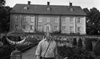 Hasselfors bruk 19 augusti 1965

I förgrunden syns en trädgårdsmästare. Bredvid honom står ett solur. Bakom honom syns en trädgård. I bakgrunden längre bort syns Hasselfors bruksbostad. En trappa i två avsatser som leder upp mot huset syns även samt längre fram i bilden några konstfärdigt klippta buskar till höger.