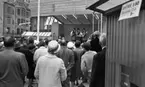 Göingeflickorna 4 september 1965

På bilden i förgrunden är det åhörare stående ute i stadsmiljö i Örebro invid 'Krämaren'. På bilden i bakgrunden är det de tre 'Göingeflickorna', klädda i folkdräkt, spelar musikinstrument och sjunger.
De tre 'Göingeflickorna' är en schlager band som var aktiv 1955 - 1975.