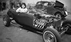 Hot rod, 7 januari 1966

I bildens förgrund syns en bil. En kvinna sitter i bilen och hon blickar in i kameran. Åskådare syns i bakgrunden.