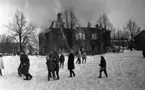 Noraskola brinner, 18 februari 1966

En vinterdag brinner det i en skola i Nora. Brandkåren är på plats för att släcka branden. De har riktat brandsprutor mot väggen för att släcka branden. I förgrunden på bilden syns det skolelever som vandrar omkring i snön.