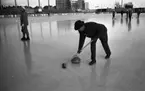 Curling på Vinterstadion, 11 februari 1965.

Åtta personer på bilden. En man i hatt spelar i förgrunden.