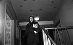 Tidningsbud 12 februari 1966

Ett tidningsbud, en kvinna, klädd i kappa och mössa står inne i ett hus på toppen av en trappa med en bunt tidningar i famnen. En lampa syns i taket i bakgrunden.