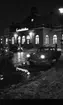 Vårregn, 31 januari 1966

Utanför Centralstationen i Örebro en regnig vinterkväll. Tre bilar står parkerade utanför byggnaden och två personer syns i bakgrunden. Det ligger snö på marken.