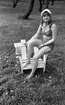 Mosåsflicka, Brandkårsuppvisning, Harar, Transportkillar 27 maj 1967

En flicka klädd i rutig bikini och vit hatt sitter på en stol utomhus i gröngräset.