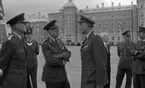 Kungen I3 28 augusti 1967

Kung Gustav VI Adolf besöker Örebro Livregementes Grenadjärer i Grenadjärsstaden. Flera män står uppställlda på regementsgården klädda i militäruniformer liksom kungen. En av militärerna har en befälsbricka runt halsen och en fana i handen. En man klädd i mörk kostym, vit skjorta och ljus slips står också bland dem.