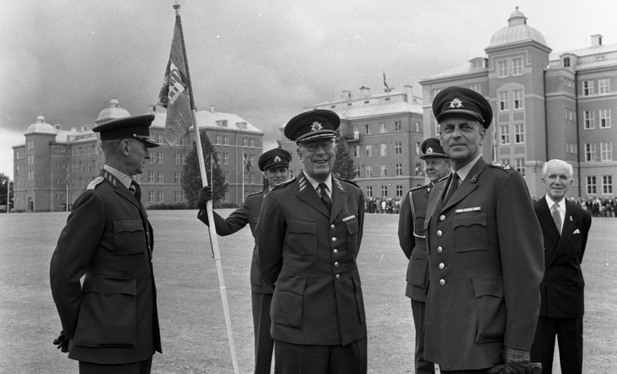 Kungen I3 28 augusti 1967

Kung Gustav VI Adolf besöker Örebro Livregementes Grenadjärer i Grenadjärsstaden. Flera män står uppställlda på regementsgården klädda i militäruniformer liksom kungen. En av militärerna har en befälsbricka runt halsen och en fana i handen. Till höger står en man i svart kostym, vit skjorta och ljus slips.