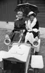 Orubricerad 21 augusti 1967. 
Två damer i 1800-talsklänningar sitter i en gammaldags vit bil i Wadköping. 
Bilen på bilden är en unik bil som byggdes cirka 1908 av fabrikör C.J. Molin i Eskilstuna. Bilen räddades långt senare av veteranbilsintresserade Torsten Johansson, Glanshammar, som renoverade den.