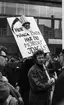 Första maj demonstration 2 maj 1967

Närbild på en man som står med en demonstrationsskylt och som är med i ett första-majtåg i centrala Örebro. På skylten överst sitter ett kranium med en hög hatt i stjärnbanerets färger och försett med hakkors. En lie sitter bredvid kraniet. På skylten står även texten: 