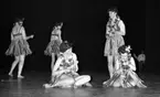 Göthman, Handikappfest,18 maj 1967

Fem kvinnor befinner sig på scenen under en revyföreställning på teatern. Alla är klädda i bikiniöverdelar, bastkjolar och har blomsterkransar runt halsarna. Två av dem sitter i förgrunden och spelar på trianglar. De tre andra står upp och dansar omkring och en av dessa kvinnor spelar också triangel.