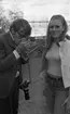 Miss Sverige 16 maj 1968

En fotomodell som är Miss Sverige klädd i vit blus med en vit jacka över och jeans med skärp i midjan samt har ett svart hårband i håret står bredvid en fotograf som har en kamera hängande i ett snöre från vänstra armen. Han är i färd med att tända en cigarrett och är klädd i ljusbrun kavaj, ljusbruna byxor, vitrandig skjorta och har glasögon på sig. De står nära järnvägsspår som syns i bildens bakgrund.