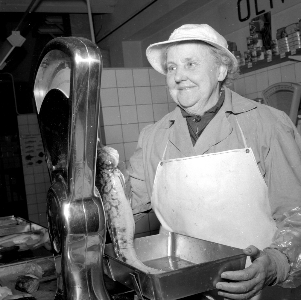 Saluhallen. Bildsidan. 
17 december 1954. 
Kvinnan på bilden hette Olivia. Delar av företagsnamnet syns i ovankant av bilden.