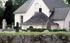 Almby kyrka med kyrkogård och klockstapel.