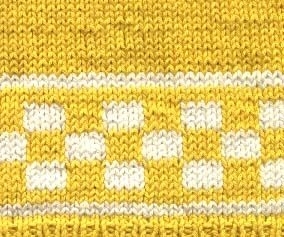Barntröja stickad i omerceriserad 
gult bomullsgarn 8/4 . 
Mönsterbård i vita rutor på gul botten.runt ärmar bål och nederkant.Virkade fastmaskor runt halsringning och luftmaskor tillknäppkant och 4 st plastknappar på ena axlen