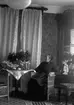 Rumsinteriör, en kvinna.
Alma Hallberg, f. Andersdotter, född 1863-10-04 vid Rostorps ägor i Sköllersta, död 1937-06-13 vid Norra Hyddan i Svennevad. (Erik Hallbergs farmor).