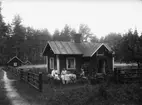 Bostadshus.
Familjegrupp fem personer vid kaffebordet framför huset.