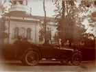 Kyrkan. 
Bilen på bilden är en Oldsmobile modell 30 från 1923-24 med en 42 hästkrafters sexcylindrig motor. Den registrerades den 2:e april 1924 på fröken Jenny Larsson, Örebro, och fick registreringsnummer T99. År 1930 ägdes den fortfarande av Jenny Larsson.