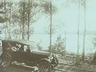 Bil på vägen framför sjön. 
Bilen är en Oldsmobile modell 30 från 1923-24 med en 42 hästkrafters sexcylindrig motor. Den registrerades den 2:e april 1924 på fröken Jenny Larsson, Örebro, och fick registreringsnummer T99. År 1930 ägdes den fortfarande av Jenny Larsson.